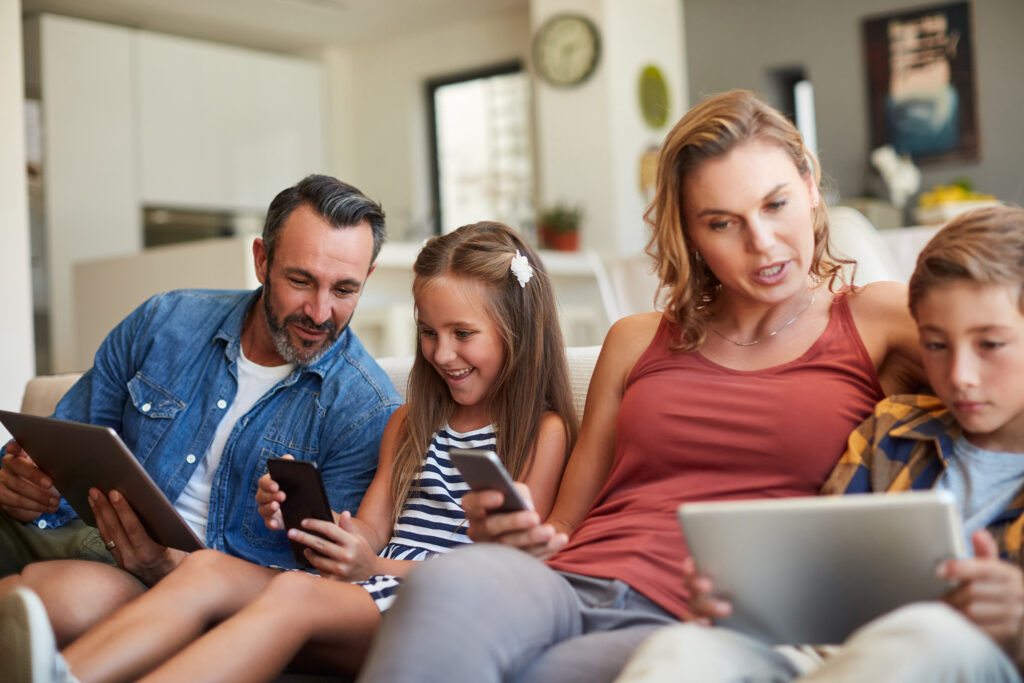 Shot of a happy young family using wireless devices on the sofa at home.