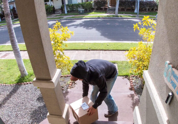 Package thief caught on video doorbell system stealing a box delivery from the front step of a suburban home